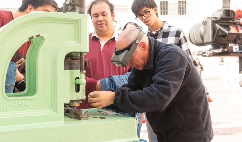 Grabador acuñando una moneda de cobre en máquina estampadora